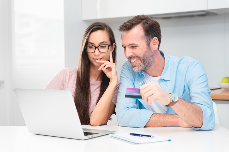 Happy couple couple e-shopping on internet. Woman using credit card, man with laptop